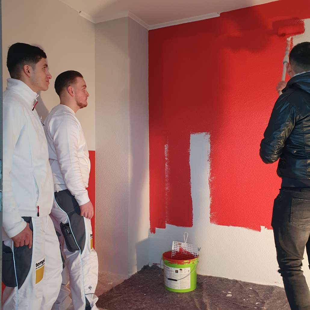 Im Rahmen des Click & Meet 2024 erleben zwei temps-Azubis wie ein Interessent eine Wand in Neustadt rot streicht